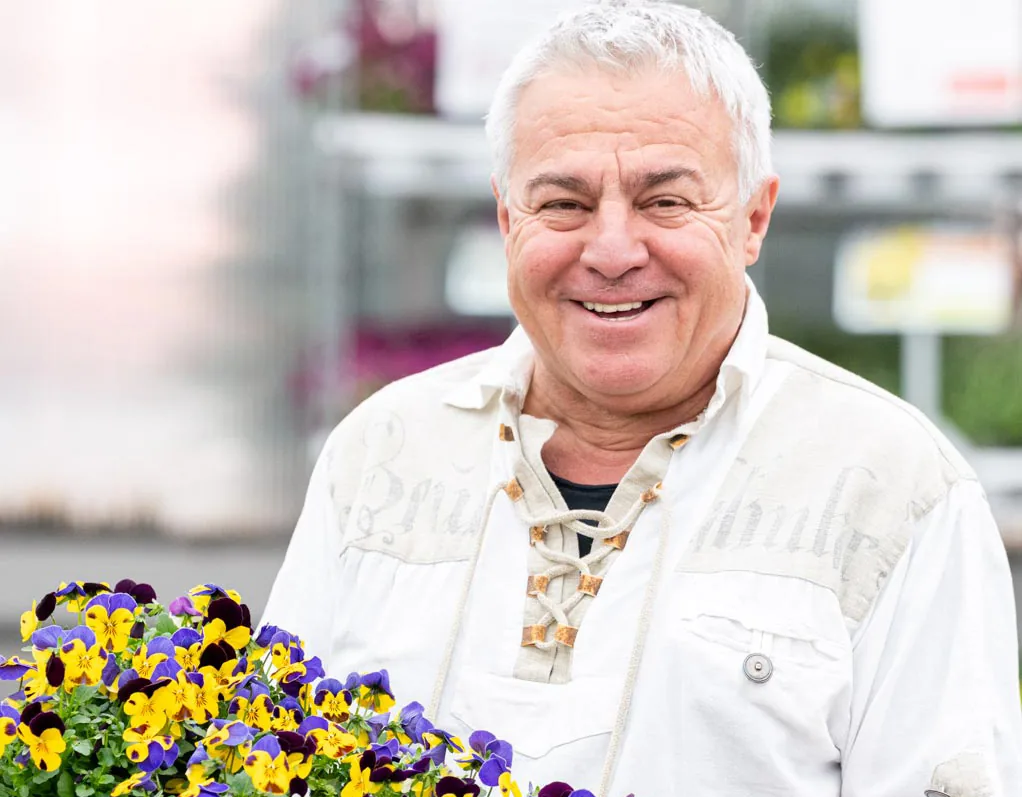 Mitarbeiter der Salzachblume mit einer Kiste bunter Stiefmütterchen